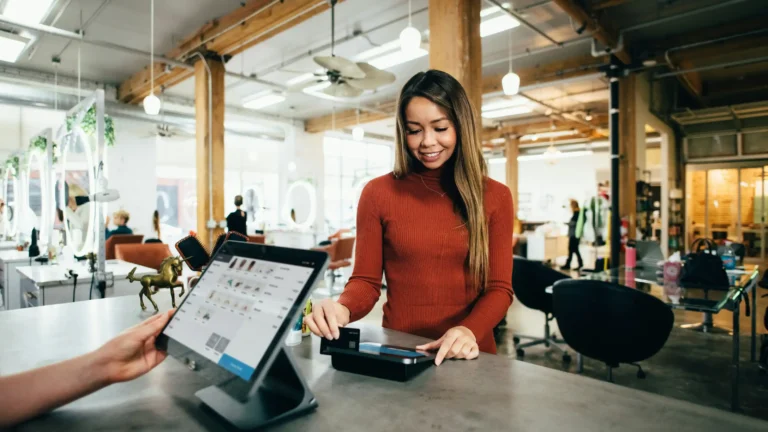 Restaurant staff is operating the POS computer, while a customer is swiping a credit card, with a smile on their face that represents satisfaction with the experience