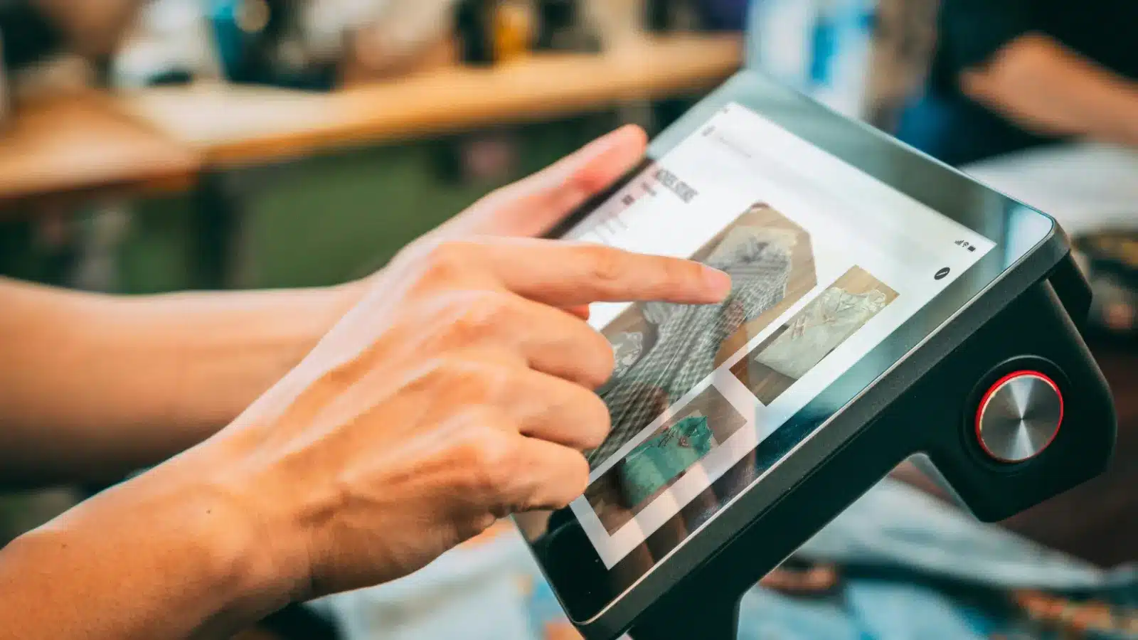 服务生正在使用一台现代化的触摸屏设备,通过点击屏幕上的菜单图片来进行点餐操作。这种数字化点餐系统提高了点餐效率,减少了出错的可能性,同时也提供了更直观的点餐体验。背景中的模糊图像表明这是一家繁忙的餐厅环境。