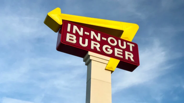 蓝天下In-N-Out Burger的标志性黄色箭头与红白招牌,快餐文化的代表。