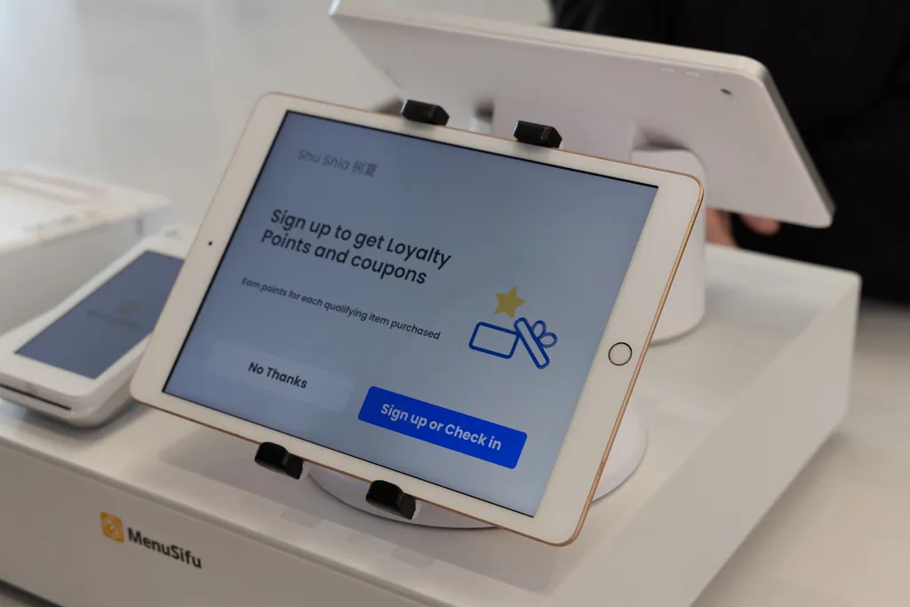 展示餐厅使用MenuSifu点餐系统的画面，顾客可通过平板注册会员、积分享优惠，体现餐饮数字化服务体验。