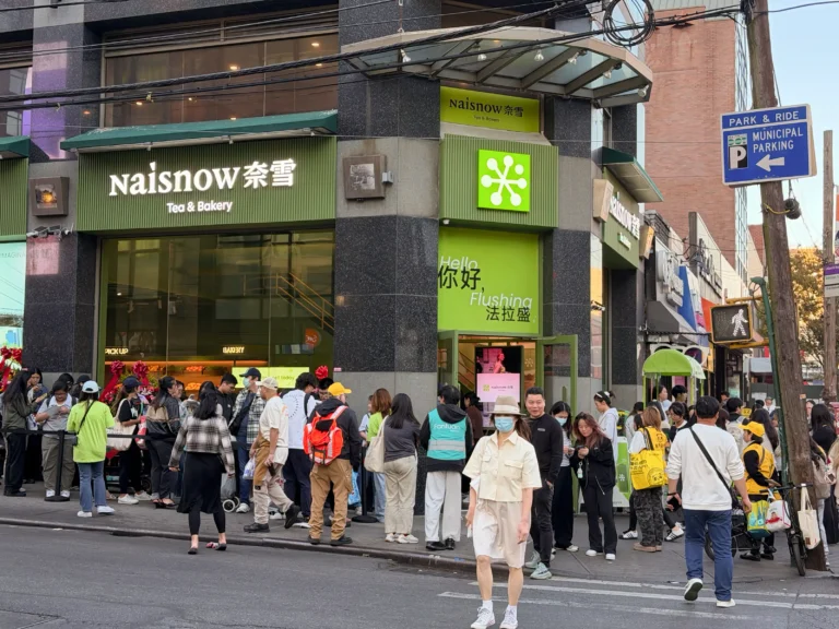 纽约法拉盛奈雪的茶门店入口实景,门口人潮涌动,顾客排队点单、取餐与合影,展现品牌在美开业人气。