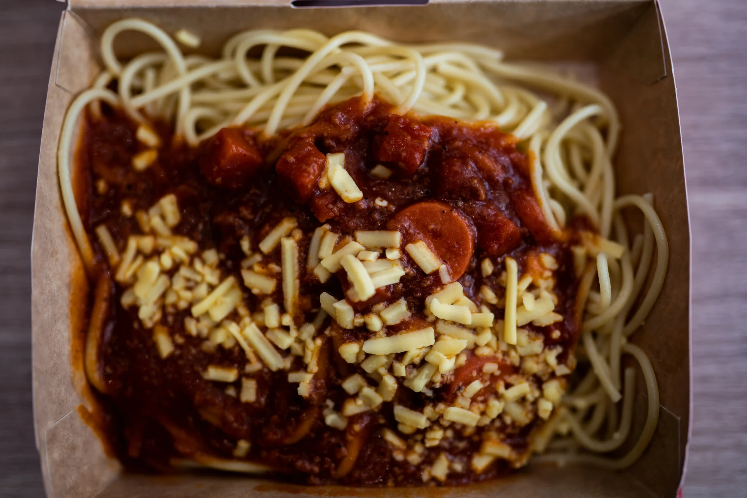 Jollibee 招牌 Jolly Spaghetti:甜番茄肉酱搭配热狗片与碎芝士,装在外带纸盒中的经典菲律宾式意大利面。