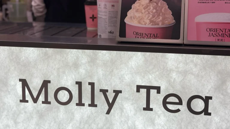 美国奶茶品牌 Molly Tea 店内实拍，包含柜台 logo、饮品海报与操作台场景，反映中国新茶饮品牌在美国城市的门店形象与产品推广方式。