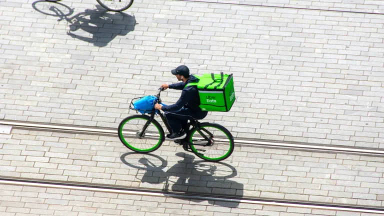 Uber Eats delivery riders delivering orders on bicycles, with images used to illustrate the Uber Eats commission hike and the rising costs of the U.S. restaurant delivery platform