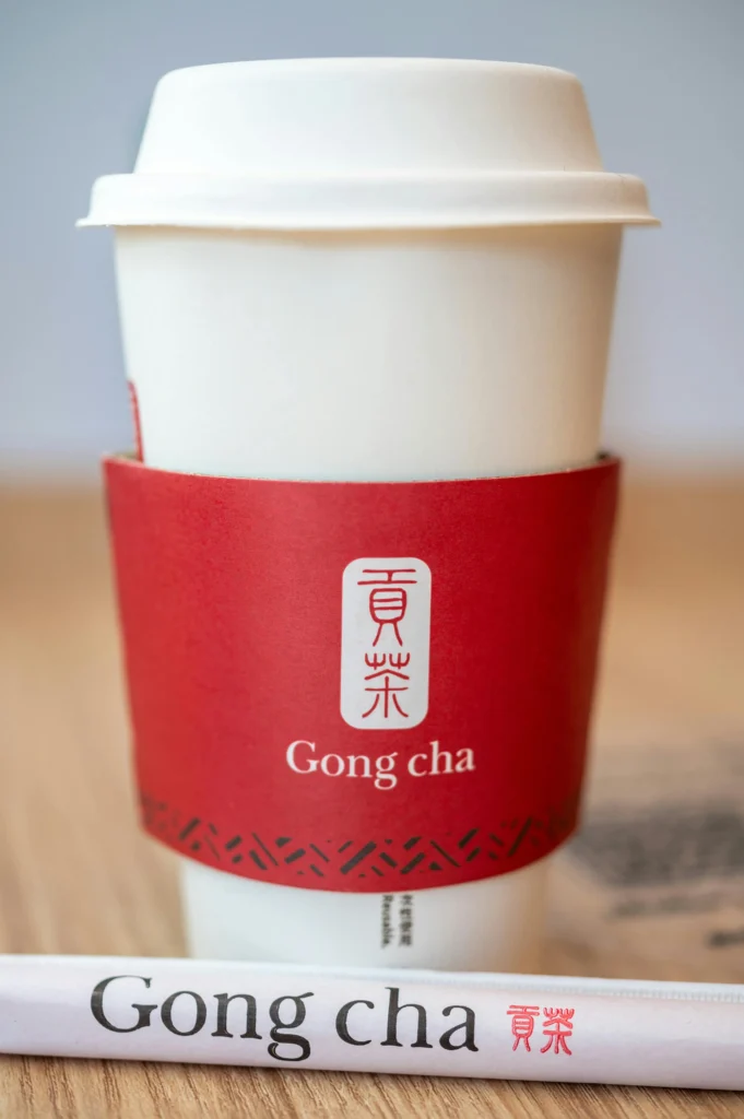 贡茶(Gong cha)热饮外带杯近景,白色杯身搭配红色杯套,展示贡茶品牌形象与包装设计