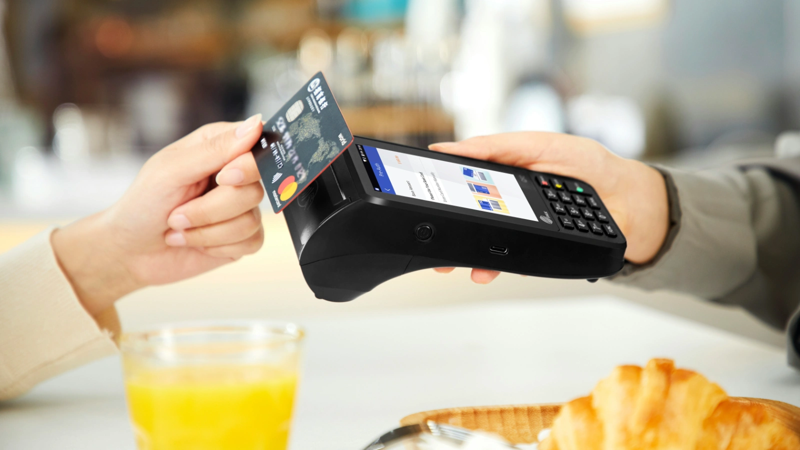 顾客在餐厅使用银行卡通过手持支付终端完成结账
