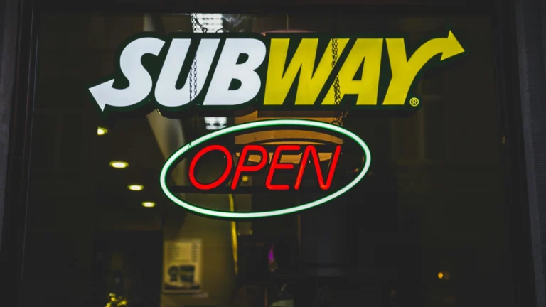 一家Subway赛百味门店的发光招牌和Open营业标识,展示美国连锁餐饮品牌的街边门店形象,可用于讨论Subway门店收缩与美国快餐连锁经营变化。
