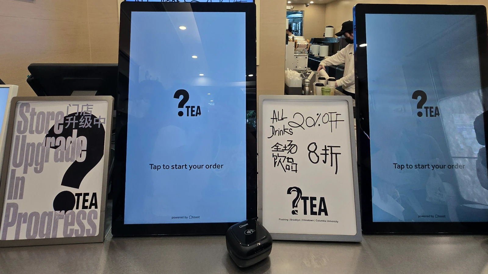 纽约原茉莉奶白门店内的自助点餐屏显示 ?Tea 标识,旁边摆放“门店升级中”和全场饮品八折促销牌。