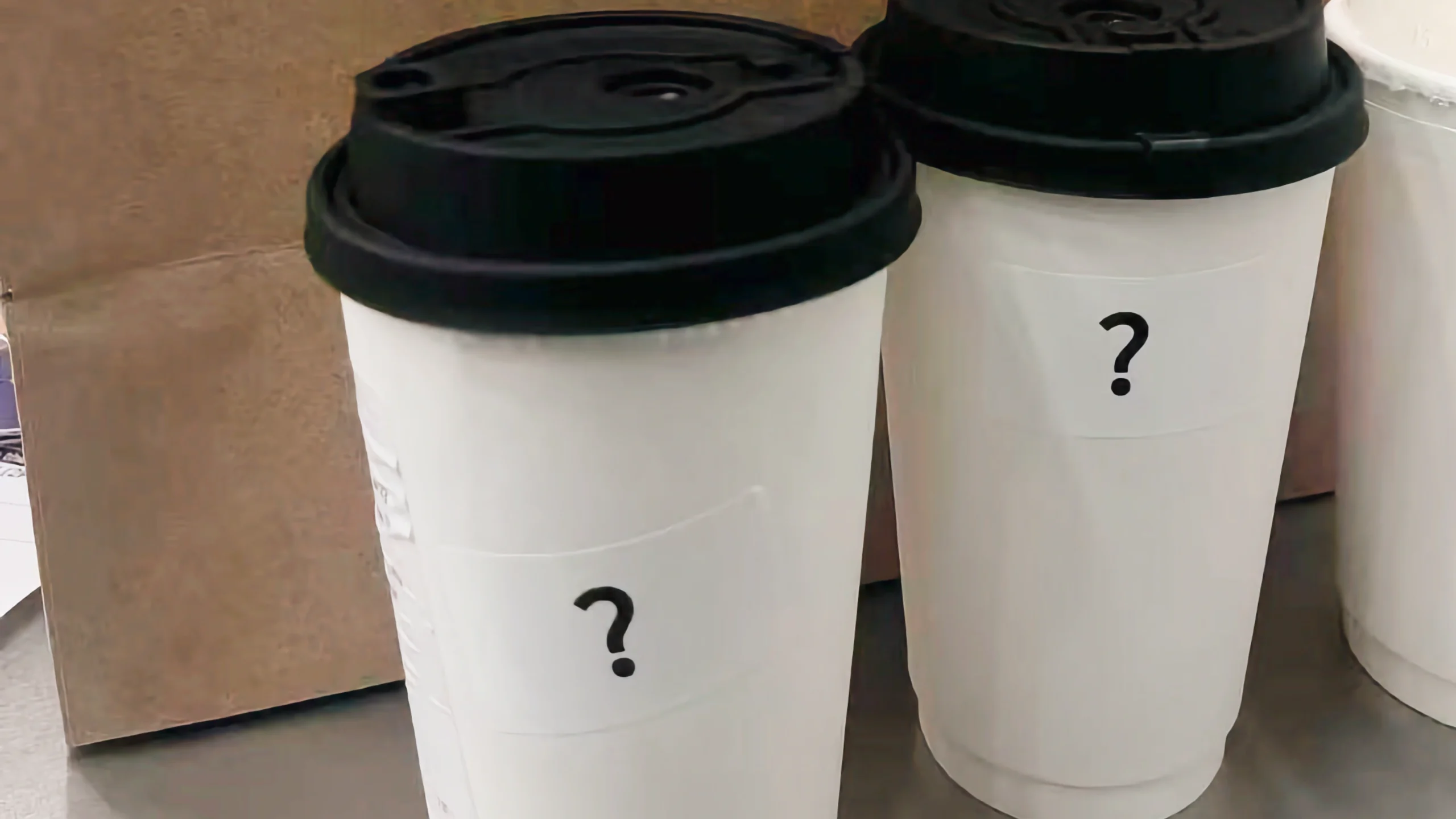 纽约原茉莉奶白门店使用白色临时饮品杯,杯身贴有黑色问号标识,体现门店更名后的去品牌化包装变化。